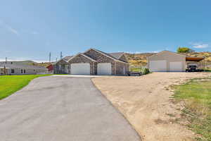 Ranch-style home with a detached garage, an outbuilding, brick siding, driveway, and a front yard