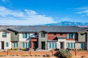 View of front facade with stone siding, stucco siding, and a fenced front yard