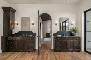 Full bath featuring two vanities and light wood-style flooring