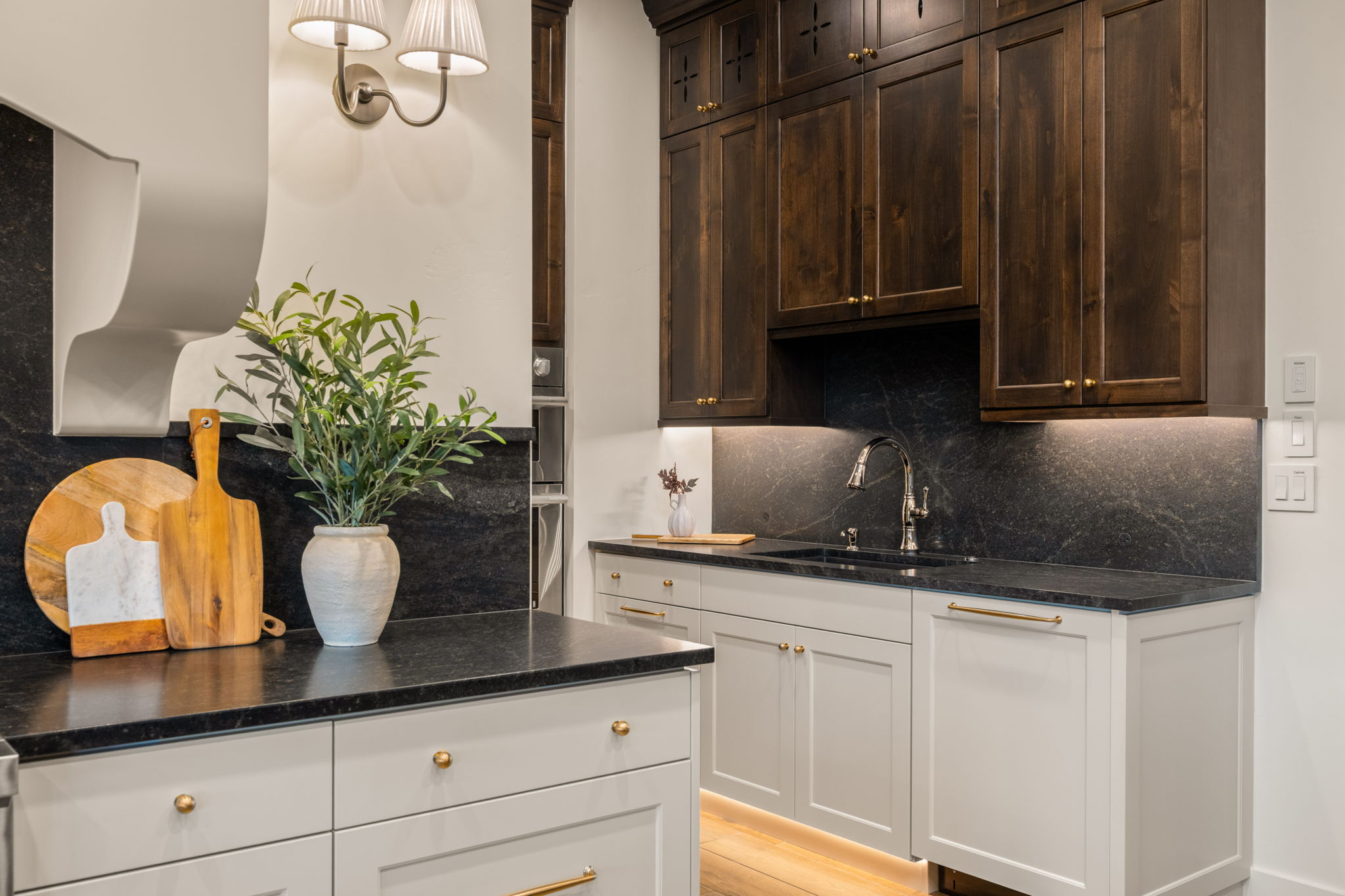 Kitchen featuring backsplash, dark stone countertops, light wood-type flooring, pendant lighting, and dark wood finish cabinetry