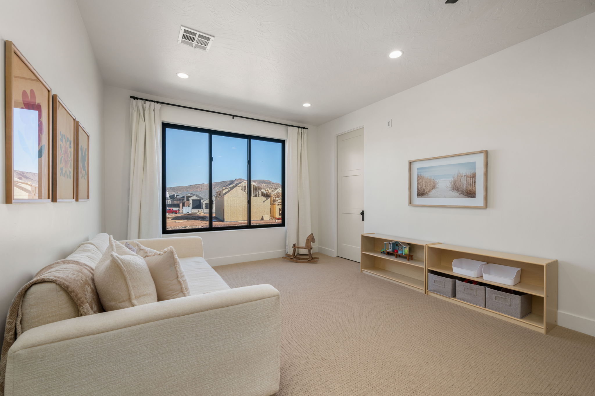 Living area with light carpet and recessed lighting