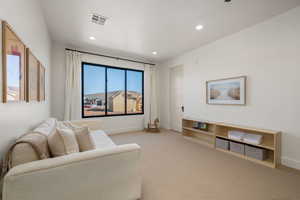 Living area with light carpet and recessed lighting