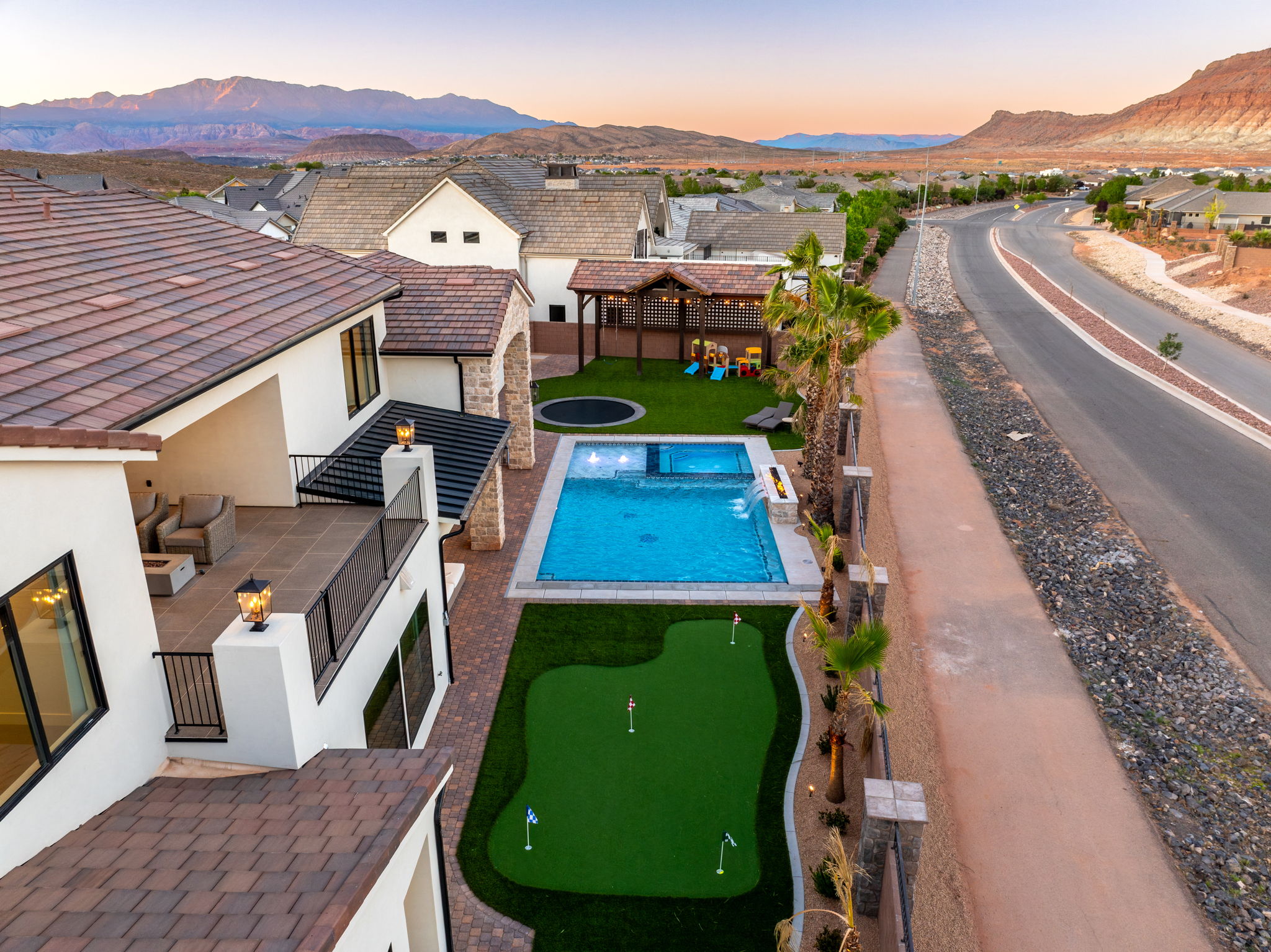 Pool at dusk with a patio, a mountain view, an area to practice putting, and a pergola