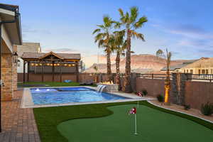 Relaxing pool / spa featuring a putting green, a patio area, a fenced backyard, and a mountain view