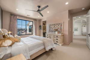 Bedroom with arched walkways, light carpet, a ceiling fan, connected bathroom, and recessed lighting