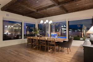 Dining area with a chandelier, a wood ceiling with exposed beams, and wood finished floors