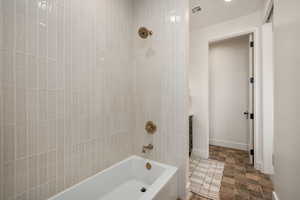 Bathroom with stone finish floors, shower / tub combination, and vanity