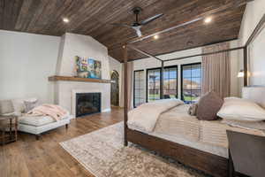 Bedroom with a vaulted wooden ceiling, recessed lighting, wood finished floors, a large fireplace, and ceiling fan
