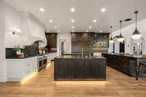 Kitchen with arched walkways, decorative light fixtures, backsplash, dark stone countertops, and two tone color scheme