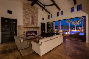 Living area featuring dark wood-style floors, a fireplace, vaulted ceiling, and a ceiling fan