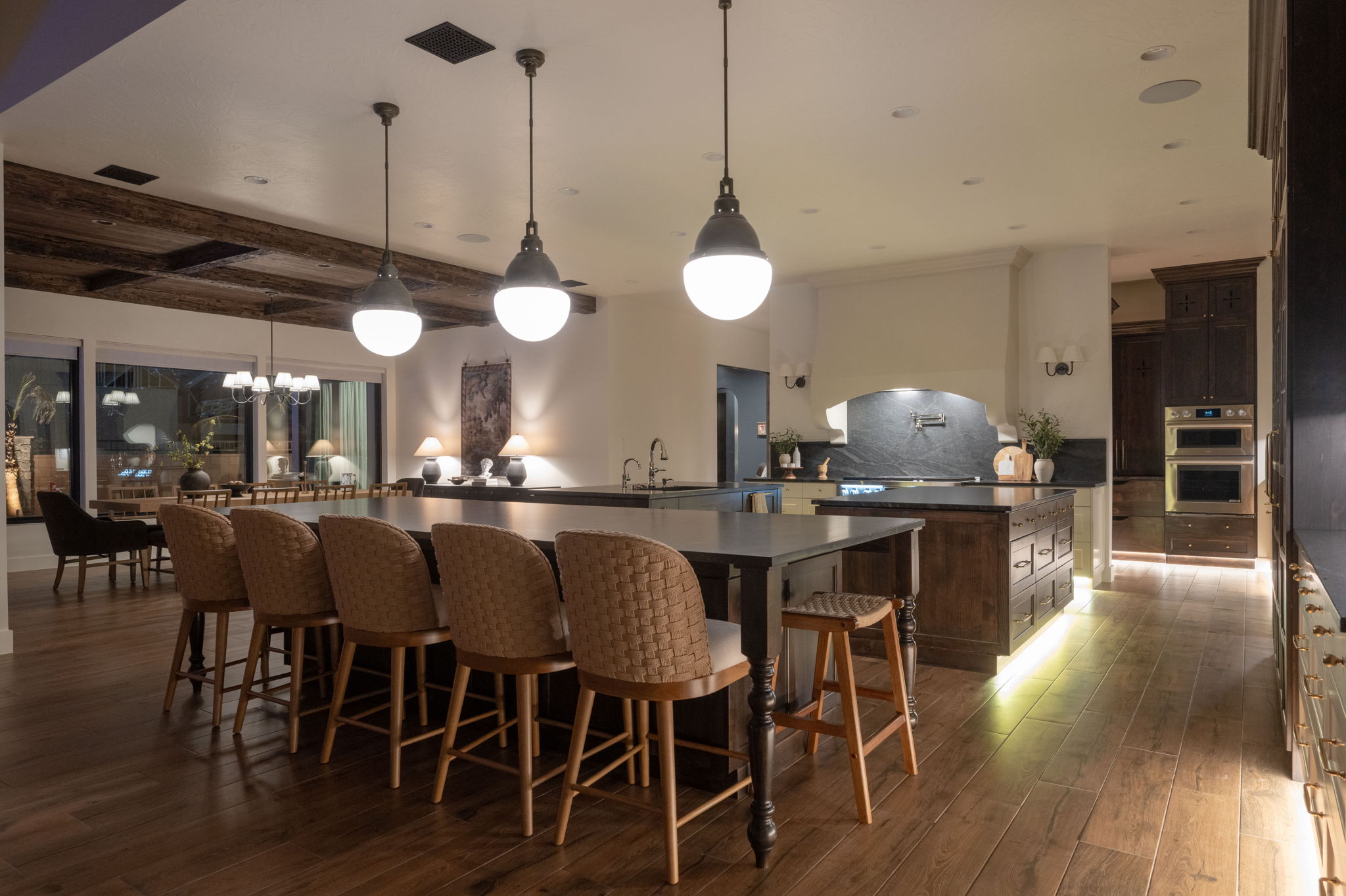 Kitchen featuring dark wood finish cabinetry, dark wood-type flooring, hanging light fixtures, a breakfast bar, and stainless steel double oven