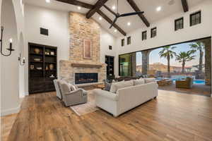 Living room with a stone fireplace, hardwood / wood-style floors, built in features, vaulted ceiling, and arched walkways