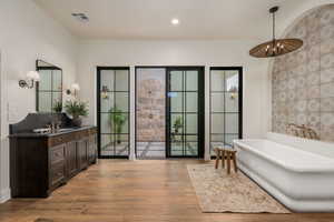 Full bathroom with vanity, a soaking tub, light wood finished floors, and recessed lighting