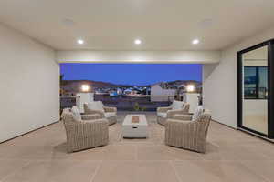 Patio at night featuring a patio area, an outdoor living space with a fire pit, and a residential view