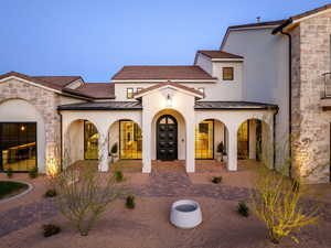 View of front facade with stone siding, a standing seam roof, stucco siding, and driveway