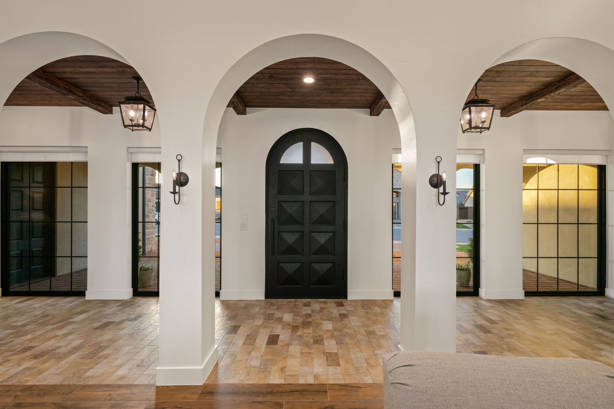 Entryway with a wood ceiling with exposed beams, arched walkways, a chandelier, and light wood-type flooring