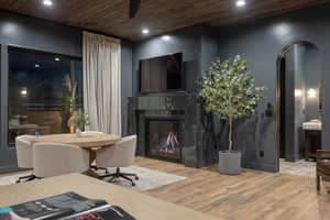 Living room featuring arched walkways, light wood finished floors, recessed lighting, a premium fireplace, and wooden ceiling