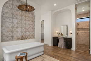 Bathroom with vanity, dark wood finished floors, a freestanding tub, a walk in closet, and a tile shower