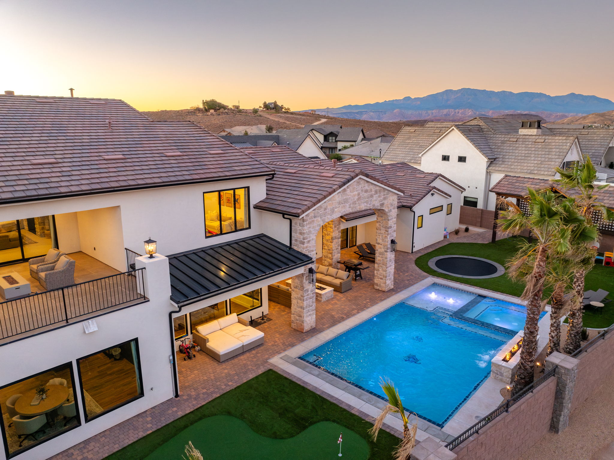 Rear view of house featuring a patio, an outdoor hangout area, an area to practice putting, stucco siding, and a pool with connected hot tub