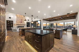 Kitchen featuring open floor plan, dark wood finish cabinetry, a fireplace, pendant lighting, and light wood finished floors