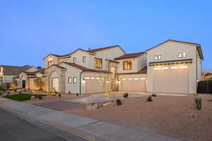 Mediterranean / spanish house with stucco siding, concrete driveway, an attached garage, and stone siding