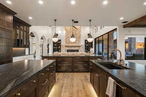 Kitchen featuring dark wood finish cabinetry, dark stone counters, and a fireplace