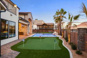 Fenced backyard with a patio and a putting area