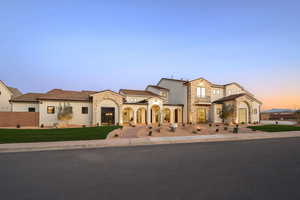 Mediterranean / spanish home with stucco siding, stone siding, a porch, and a lawn
