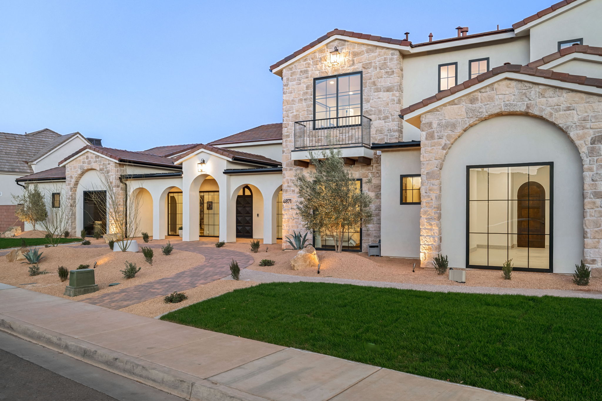 Mediterranean / spanish-style home featuring stucco siding, stone siding, a balcony, and a front lawn