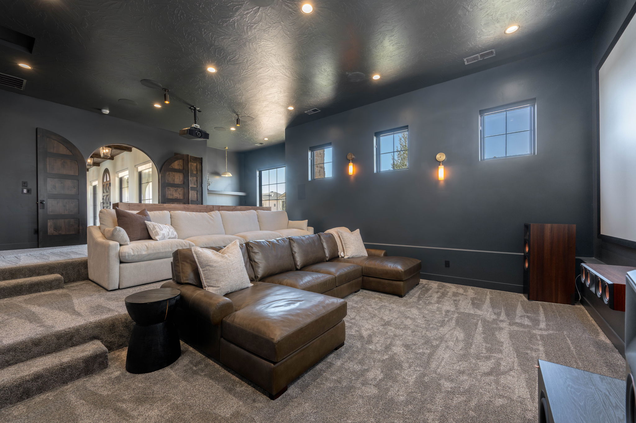 Home theater featuring arched walkways, carpet floors, a textured ceiling, and track lighting