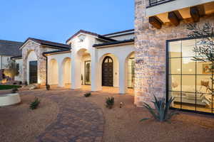Property entrance with stone siding, stucco siding, and a tiled roof