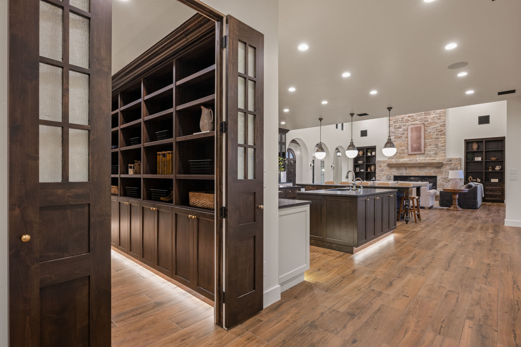 Corridor with recessed lighting, light wood-style flooring, built in shelves, and arched walkways