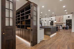 Corridor with recessed lighting, light wood-style flooring, built in shelves, and arched walkways