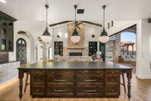 Kitchen featuring arched walkways, dark wood finish cabinets, a kitchen bar, glass fronted cabinets, and open floor plan