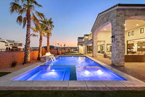 Pool at dusk featuring a patio area, a fenced backyard, and a pool with connected hot tub
