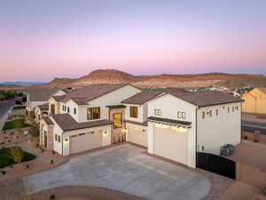 Mediterranean / spanish-style house featuring stucco siding, concrete driveway, stone siding, and a mountain view