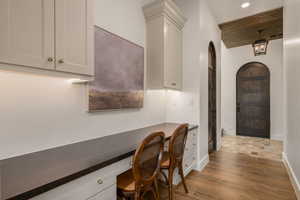 Office space featuring built in desk, arched walkways, dark wood-style flooring, recessed lighting, and wood ceiling