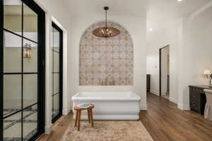 Bathroom with a freestanding tub, dark wood-type flooring, and vanity