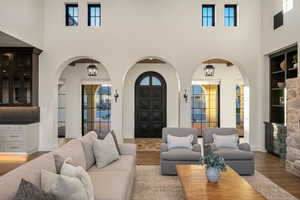 Living area featuring arched walkways, wood finished floors, a high ceiling, french doors, and built in features