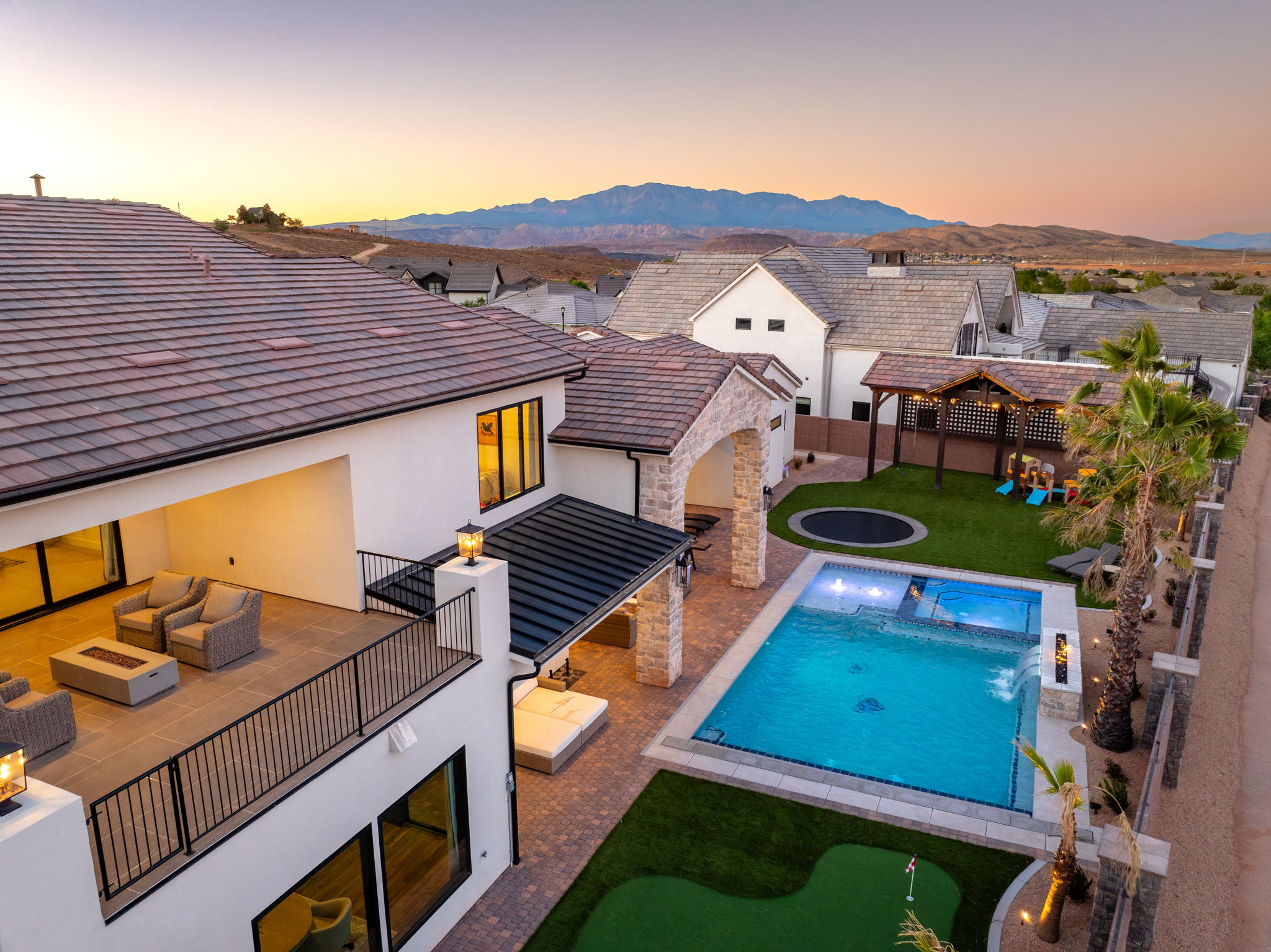 View of pool with patio surround, an outdoor living space with a fire pit, a putting green, a fenced backyard, and a mountain view