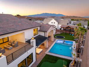 View of pool with patio surround, an outdoor living space with a fire pit, a putting green, a fenced backyard, and a mountain view