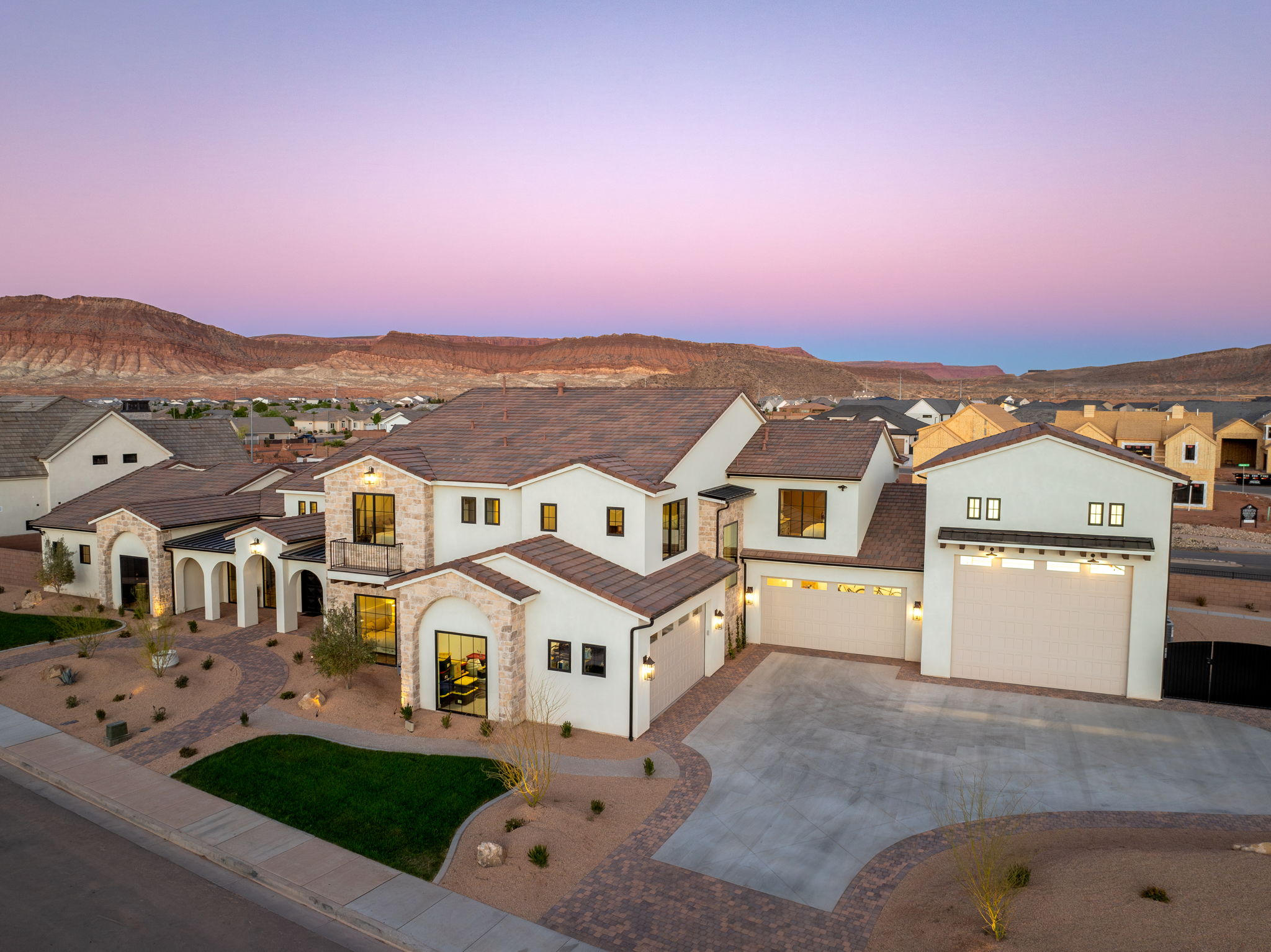 View of front of property featuring a residential view, concrete driveway, stucco siding, stone siding, and a mountain view