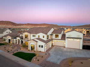 View of front of property featuring a residential view, concrete driveway, stucco siding, stone siding, and a mountain view