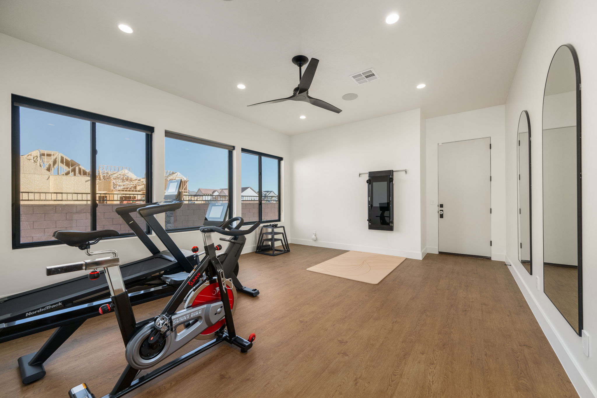 Workout room featuring ceiling fan, wood finished floors, recessed lighting, and arched walkways