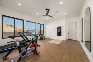 Workout room featuring ceiling fan, wood finished floors, recessed lighting, and arched walkways