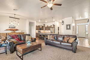 Living area featuring a ceiling fan, a textured ceiling, and light wood-type flooring