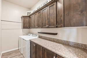 Laundry room with cabinet space, washing machine and dryer, and light wood-style flooring