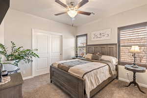 Bedroom with dark colored carpet, a closet, and a ceiling fan