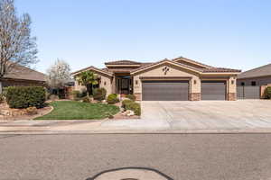 Mediterranean / spanish house featuring stone siding, stucco siding, a garage, a front yard, and driveway