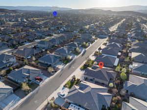 Aerial view of property and surrounding area featuring mountains and nearby suburban area